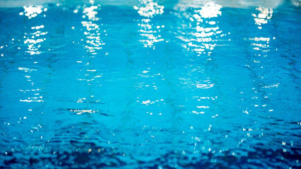 Wasseroberfläche mit Lichtreflexionen in verschiedenen Blau- und Türkistönen. Sanfte Wellenbewegungen sichtbar.